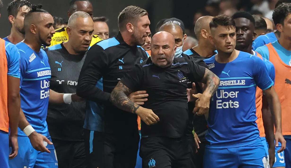 Para pemain Marseille beserta official tim, termasuk pelatih Jorge Sampaoli (tengah) segera digiring menuju lorong stadion untuk meninggalkan lapangan agar terhindar dari amarah para suporter Nice. (Foto: AFP/Valery Hache)