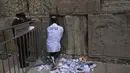 Pekerja memindahkan catatan doa yang ditinggalkan pengunjung dari celah di antara batu-batu di Tembok Barat, situs paling suci tempat orang Yahudi dapat berdoa di Kota Tua Yerusalem, Selasa, 20 September 2022, menjelang Rosh Hashana, Tahun Baru Yahudi. Catatan dimakamkan di pemakaman terdekat menurut tradisi Yahudi. Operasi dilakukan dua kali setahun sebelum Rosh Hashana dan sebelum liburan Paskah di musim semi. (AP/Mahmoud Illean)