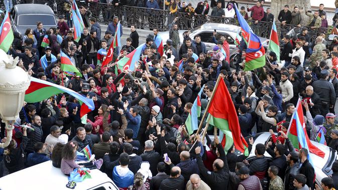Rakyat Azerbaijan mengibarkan bendera nasional di Ganja, Azerbaijan, Selasa (10/11/2020). Armenia dan Azerbaijan mengumumkan perjanjian damai untuk menghentikan pertempuran atas wilayah Nagorno-Karabakh di Azerbaijan berdasarkan pakta yang ditandatangani dengan Rusia. (AP Photo/Aydin Mammedov)