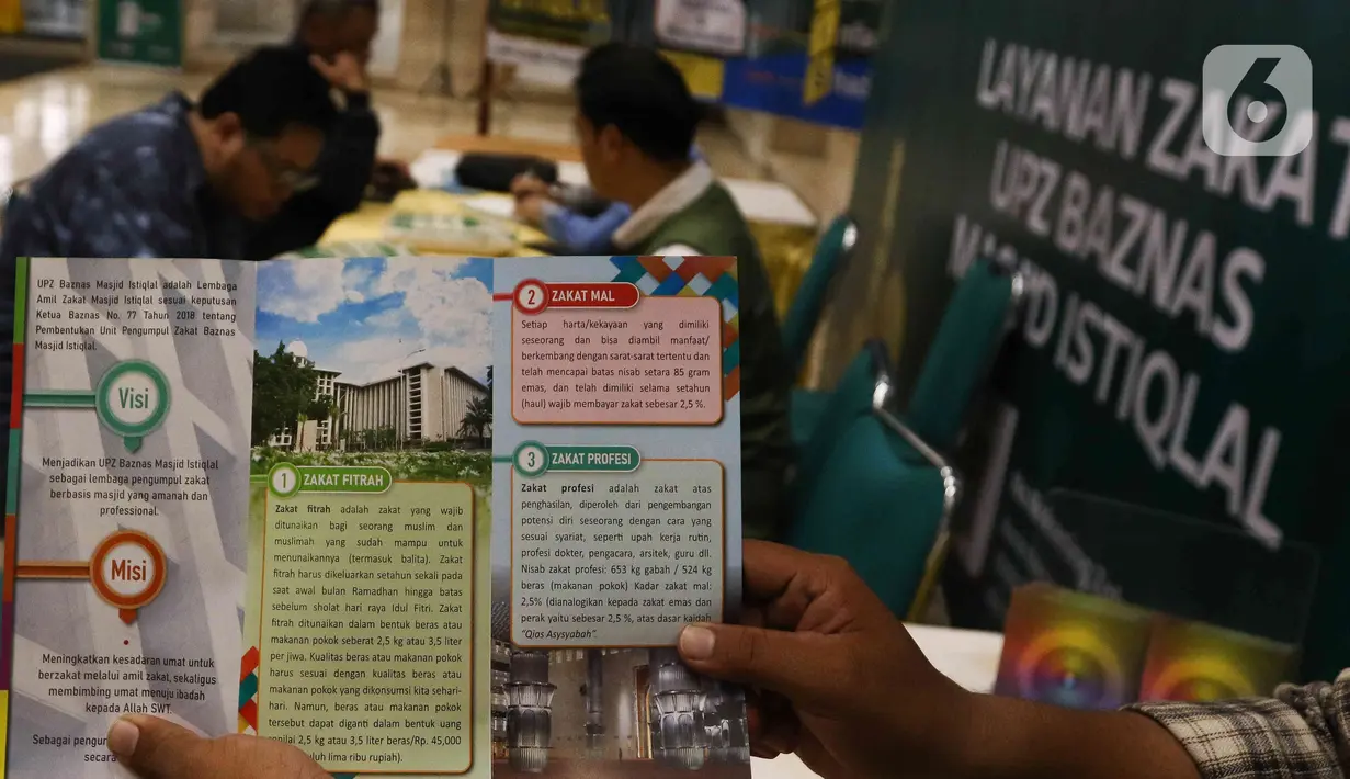 Petugas amil zakat Masjid Istiqlal menunjukkan brosus seputar zakat fitrah. (Liputan6.com/Herman Zakharia)
