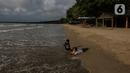Dua anak bermain di tepi pantai Carita, Pandeglang, Banten, Selasa (18/1/2022). Objek wisata Pantai Carita yang menjadi tempat favorit pengunjung kini tampak sepi seusai gempa beberapa waktu lalui dan juga lantaran naikknya kasus virus covid 19 varian omicron. (Liputan6.com/Johan Tallo)