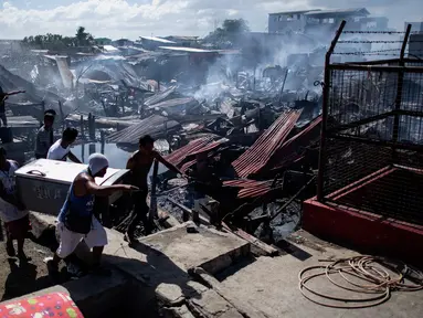 Sejumlah warga membawa barang miliknya saat rumah-rumah mereka hangus terbakar di sebuah daerah kumuh di Navotas, Manila (8/11). Dilaporkan sekitar 150 keluarga terkena dampak kebakaran tersebut. (AFP Photo/Noel Celis)