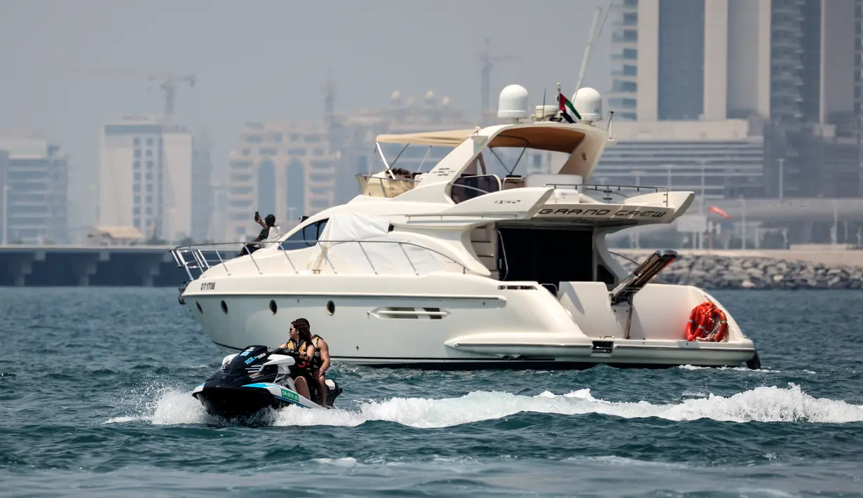 Sebuah kapal pesiar mewah digambarkan dari Dubai Marina Beach di emirat Teluk, 10 Juni 2021. Di tengah aturan pandemi di mana warga harus menjaga jarak dan menghindari keramaian, orang-orang kaya di Dubai memiliki cara untuk bisa pergi berekreasi, yaitu mode wisata kapal pesiar. (Karim SAHIB/AFP)