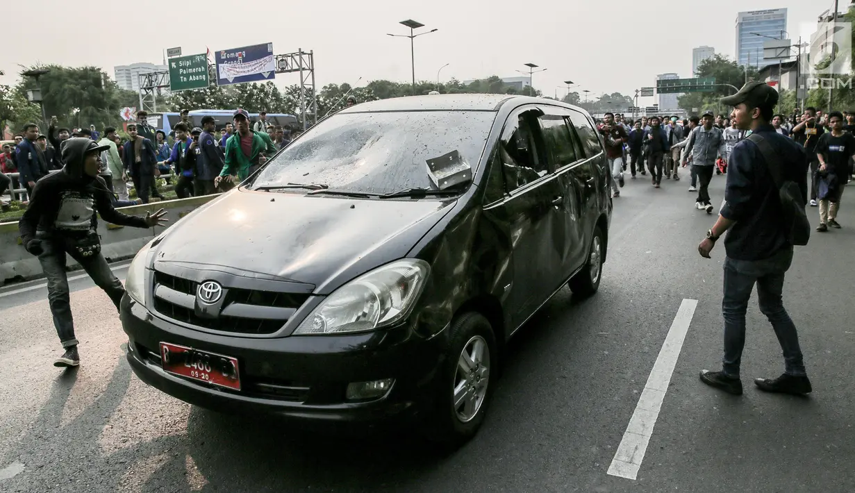 Mobil pelat nomor merah dilempari oleh massa aksi saat melintasi jalan tol seberang Gedung DPR/ MPR RI, Jakarta, Selasa (24/9/2019). Selain menutup ruas tol, kendaraan dinas pemerintah dan milik polisi jadi korban pelemparan dan perusakan oleh mahasiswa. (Liputan6.com/Faizal Fanani)