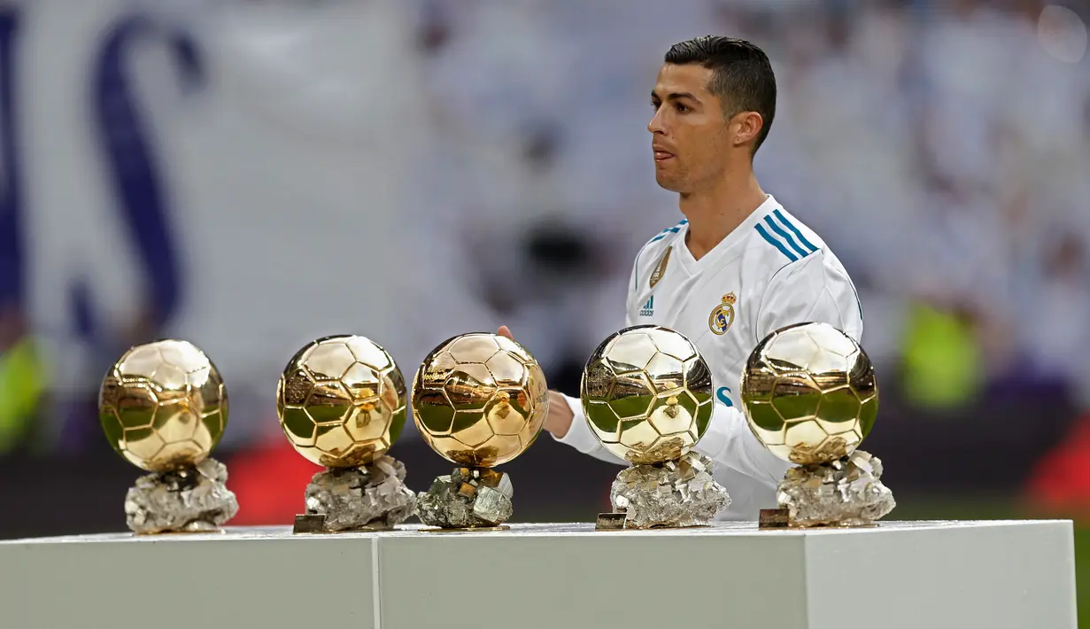 Bintang Real Madrid, Cristiano Ronaldo berpose dengan kelima trofi Ballon d'Or sebelum laga Real Madrid vs Sevilla di Stadion Santiago Bernabeu, Sabtu (9/12). Ronaldo baru saja meraih trofi kelima penghargaan Ballon d'Or 2017 di Paris. (AP/Francisco Seco)