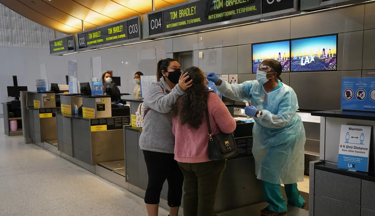 Petugas kesehatan mengambil sampel usap hidung dari pelancong di lokasi pengujian COVID-19 di Bandara Internasional Los Angeles, 23 November 2020. Menjelang Thanksgiving, Pusat Pengendalian Penyakit mengimbau agar orang Amerika tak bepergian di tengah lonjakan Covid-19 di AS. (AP Photo/Jae C. Hong)