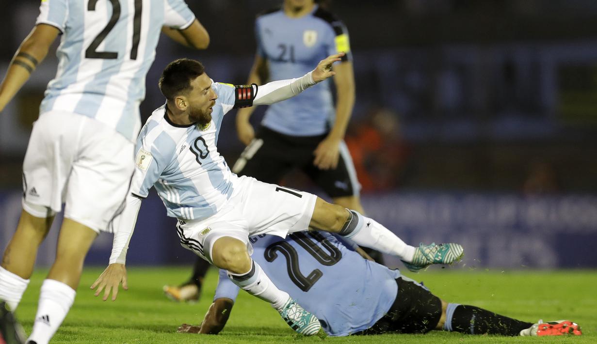 Pemain Argentina, Lionel Messi terjatuh saat berebut bola dengan pemain Uruguay, Alvaro Gonzalez pada laga kualifikasi Piala Dunia 2018 di Montevideo, Uruguay, (31/8/2017). Argentina bermain imbang 0-0. (AP/Natacha Pisarenko)