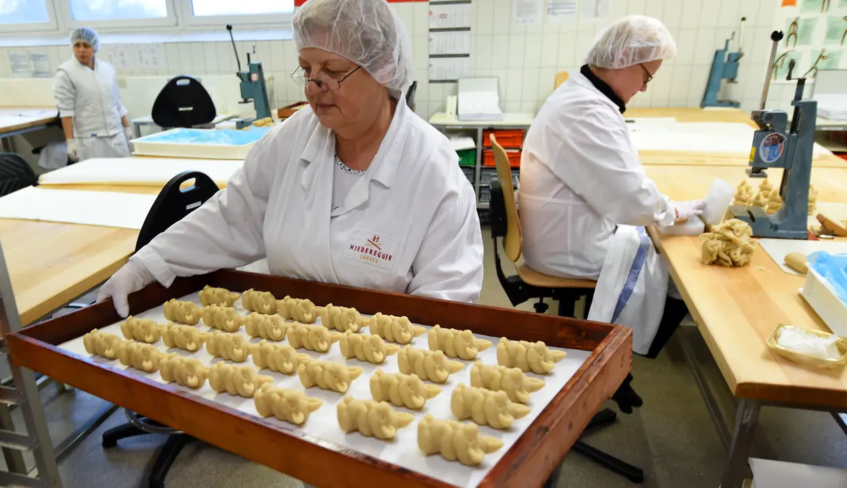 Pekerja membawa adonan kue yang akan di oven di tempat pembuatan tradisional JG Niederegger GmbH di Luebeck, Jerman (5/12). Camilan unik ini merupakan makanan khas dari Luebeck, sebuah kota yang berada di utara Jerman. (AFP Photo/Stollarz)