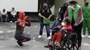 Seseorang yang mengenakan kostum Spiderman menyapa seorang wanita di atas kursi roda setelah disuntik vaksin covid-19 Pfizer-BioNTech di Mexico City, Meksiko, Selasa (28/12/2021). Spiderman tersebut dipekerjakan oleh Pemerintah Kota untuk menghibur para peserta vaksinasi. (ALFREDO ESTRELLA / AFP)