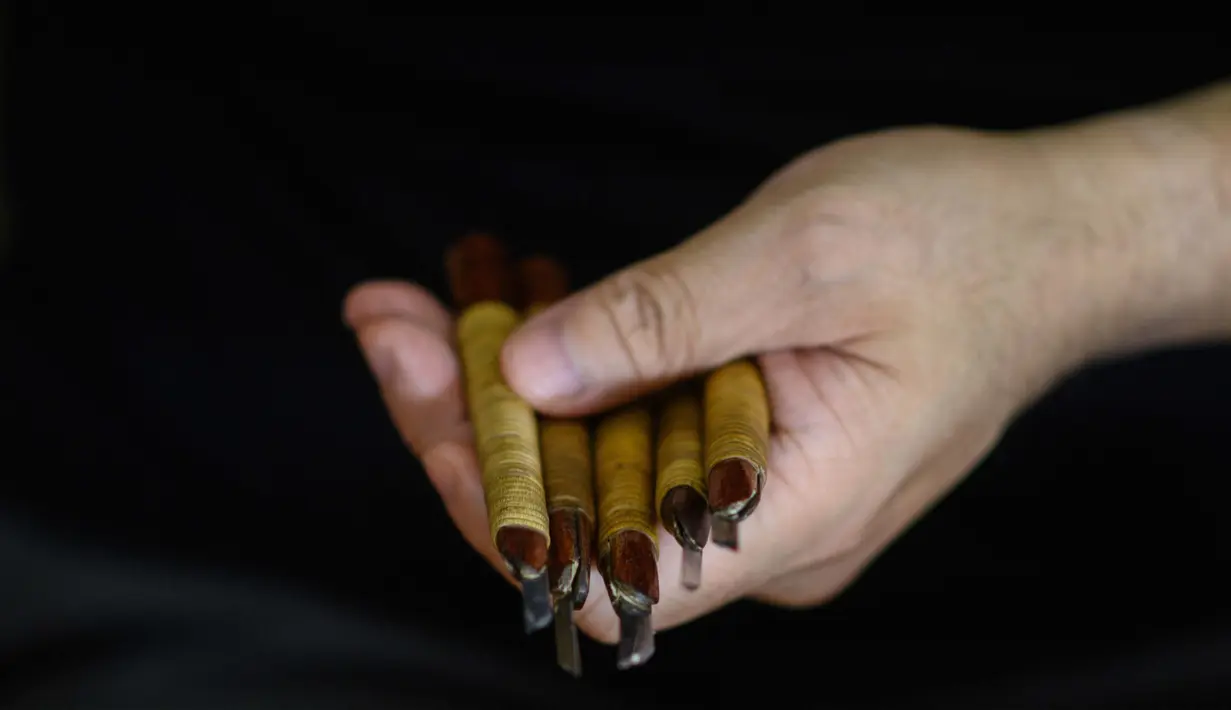 Pembuat stempel tinta tradisional Takahiro Makino, 44, memegang alat untuk mengukir saputangan di di Tokyo pada 9 Oktober 2020. Hanko atau stempel tinta tradisional digunakan menandatangani segala sesuatu mulai dari tanda terima pengiriman hingga sertifikat pernikahan di Jepang. (Philip FONG/AFP)