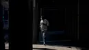 Seorang pria berjalan di sepanjang jalan yang sepi di Sydney (21/8/2021). Kota itu memperpanjang penguncian selama dua bulan dan memberlakukan jam malam sebagian untuk menahan wabah virus corona yang menyebar cepat. (AFP/David Gray)