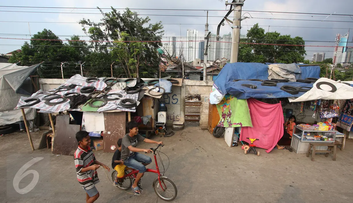 Sejumlah anak bersepeda melewati gubuk liar yang didirikan di jalur inspeksi KBB, Kebon Melati, Jakarta, Rabu (1/6). Meski berulang kali ditertibkan, warga tak jera untuk kembali membangun gubuk liar di kawasan tersebut. (Liputan6.com/Immanuel Antonius)
