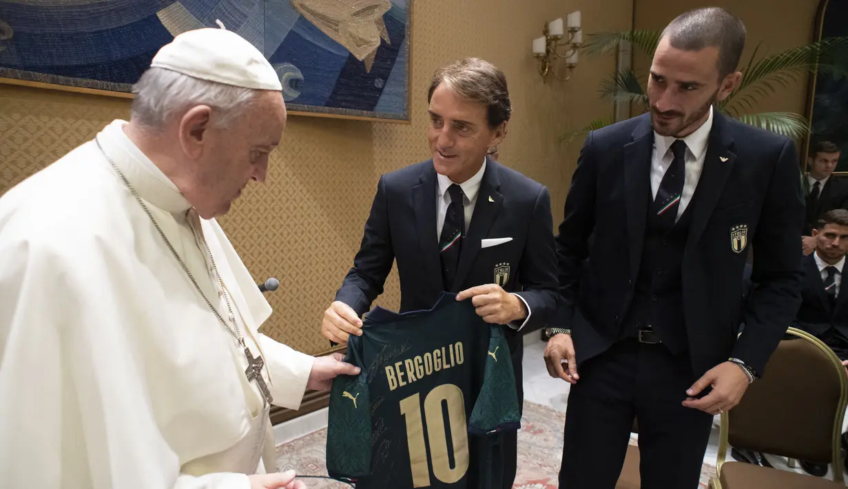 Pelatih Italia, Roberto Mancini (tengah) memberikan jersey Timnas Italia kepada Paus Fransiskus saat mengikuti misa kanonisasi untuk John Henry Newman dari Inggris, Giuseppina Vannini dari Italia, Maria Teresa Chiramel Mankidiyan dari India, Dulce Lopes Pontes dari Brasil, dan Margarita Bays dari Swiss di Vatikan pada 13 Oktober 2019. (AFP/Vatican Media)