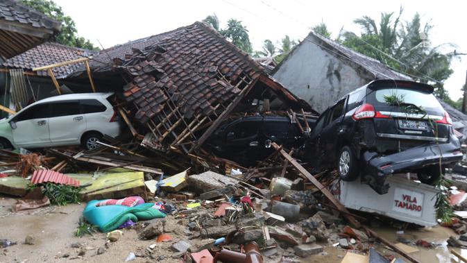 Dua unit mobil tertimbun reruntuhan rumah yang rusak setelah tsunami menerjang kawasan Anyer, Banten, Minggu (23/12). Data sementara jumlah korban dari bencana tsunami di Selat Sunda tercatat 168 orang meninggal dunia. (Liputan6.com/Angga Yuniar)