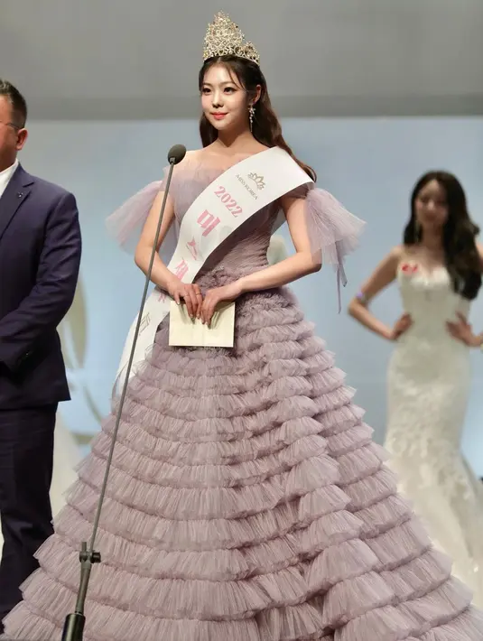 Choi Min Ji juga ternyata pernah dinobatkan menjadi Miss Jeju di tahun 2022. Di foto ini, Min Ji tampil menawan dalam balutan gaun megah dengan aksen tingkat bernuansa abu-abu yang cantik. [Foto: Instagram/joymingzi_]