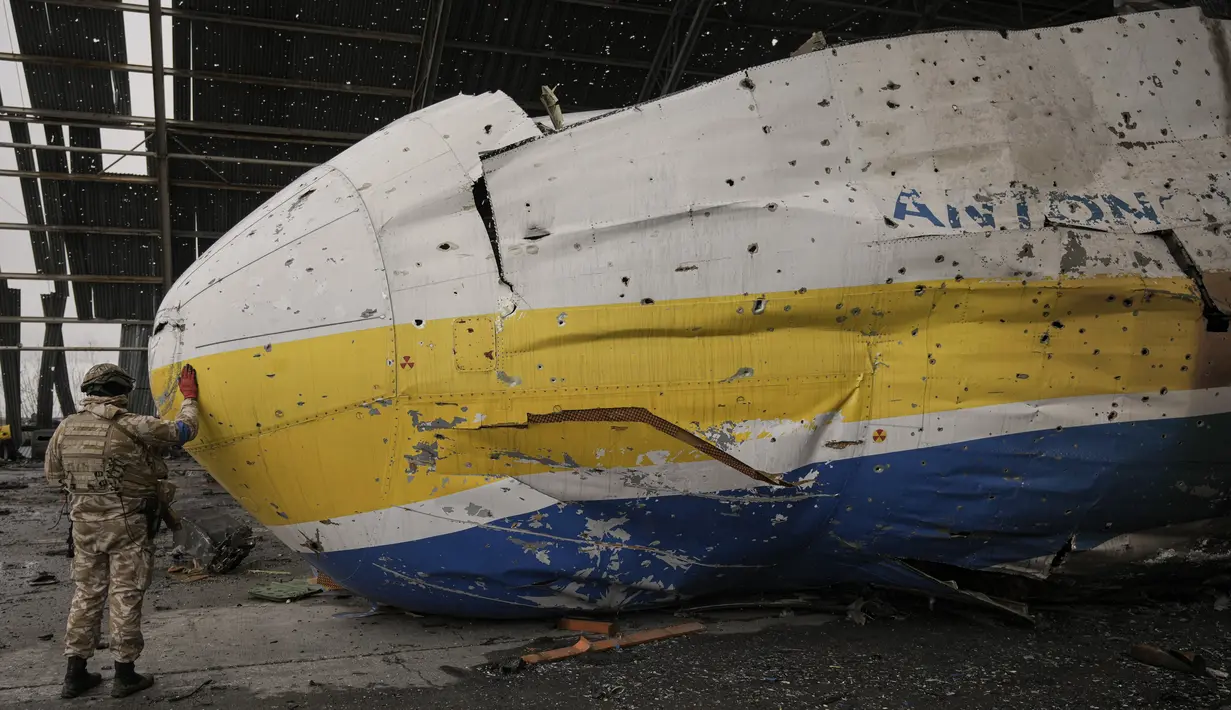 Prajurit Ukraina menyentuh hidung pesawat Antonov An-225 Mriya di bandara Antonov di Hostomel, 2 April 2022. Di pintu masuk Bandara Antonov, pasukan menjaga posisinya, tanda mereka memegang kendali penuh atas landasan pacu yang coba diserbu Rusia di hari-hari pertama perang. (AP Photo/Vadim Ghirda)