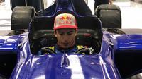 Marc Marquez sedang duduk disebuha mobil balap F1 milik tim RedBull. (GPOne)