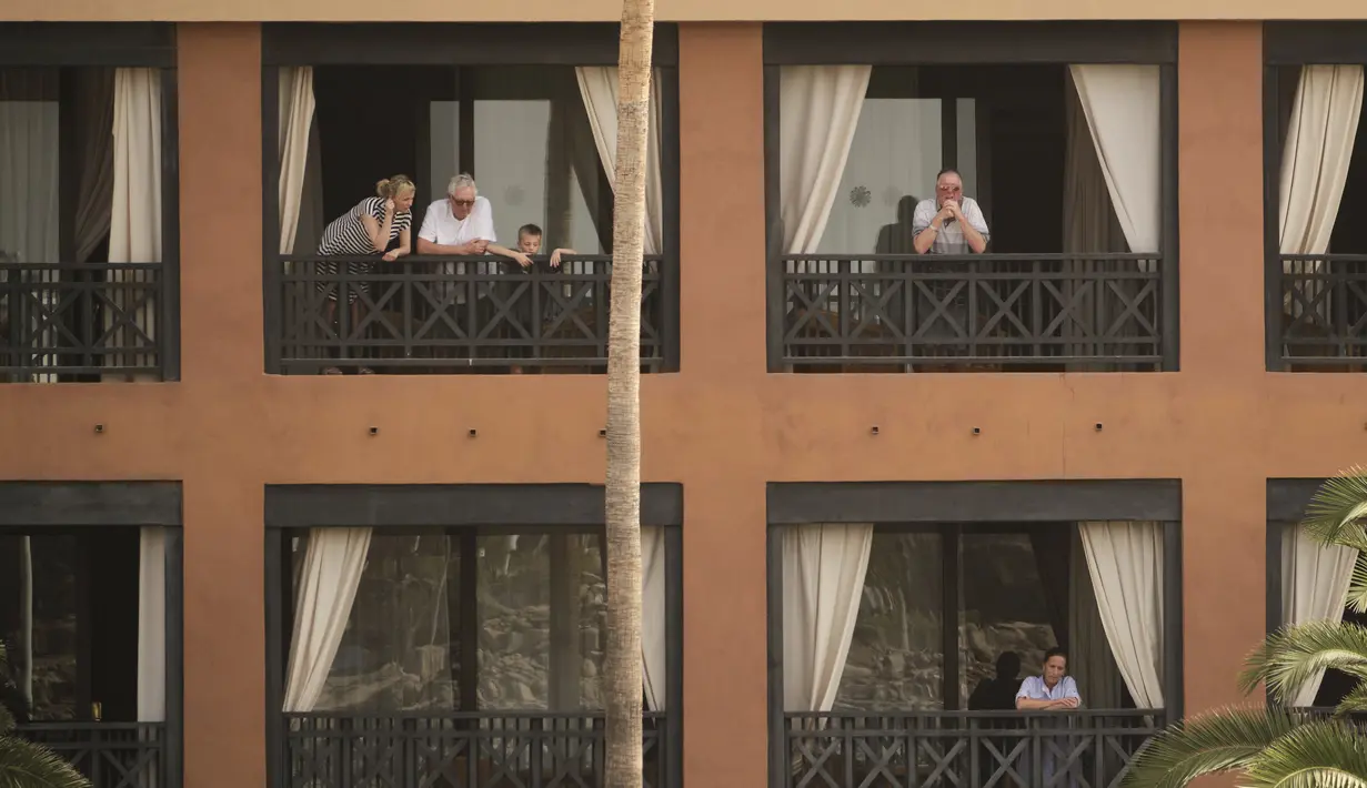 Orang-orang berdiri di balkon mereka di hotel H10 Costa Adeje Palace di Pulau Canary Tenerife, Spanyol, Selasa, (25/2/2020). Pemerintah Spanyol mengatakan sekitar 1.000 orang di Hotel H10 tersebut diisolasi usai adanya temuan positif virus corona COVID-19. (AP Photo)
