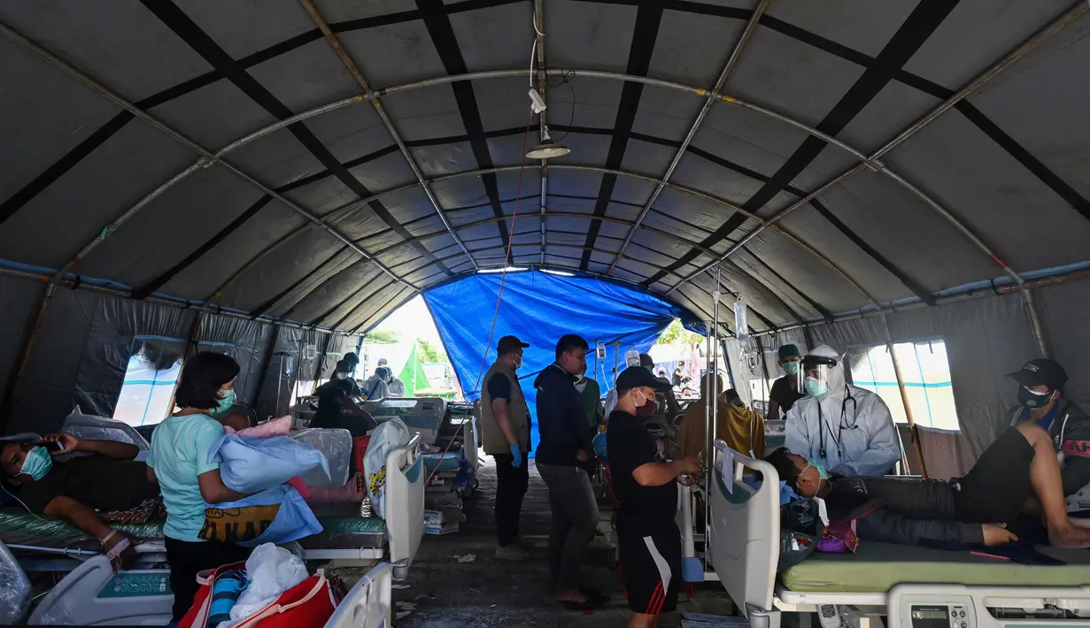 Pasien menerima perawatan di tempat penampungan sementara di luar Rumah Sakit Regional Sulbar, Mamuju, Minggu (17/1/2021). Mereka dirawat di dalam tenda darurat untuk mengantisipasi gempa susulan pascagempa 6,2 yang mengguncang Majene dan Mamuju, Sulawesi Barat pada Jumat (15/1). (ADEK BERRY/AFP)