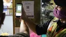 Petugas membantu pengunjung melakukan scan QR code melalui aplikasi PeduliLindungi di Pasar Anyar, Tangerang, Selasa (26/10/2021). PD Pasar Kota Tangerang memberlakukan penerapan aplikasi PeduliLindungi di dua pasar tradisional, yakni Pasar Anyar dan Pasar Poris. (Liputan6.com/Angga Yuniar)