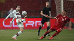 Gelandang Portugal, Bruno Fernandes (kiri) mengontrol bla di depan gelandang Serbia, Sergej Milinkovic-Savic dalam laga Kualifikasi Piala Dunia 2022 Zona Eropa Grup A di Rajko Mitic Stadum, Belgrade, Sabtu (27/3/2021). Portugal bermain imbang 2-2 dengan Serbia. (AFP/Pedja Milosavljevic)