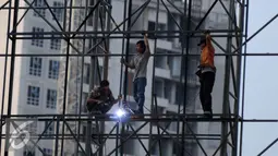 Pekerja mengelas rangkaian besi untuk pembuatan papan reklame di jalan Gadjah Mada, Jakarta, Selasa (13/12). Pemerintah DKI Jakarta akan menyusun rencana penataan terhadap reklame yang tidak beraturan di jalur protokol. (Liputan6.com/Gempur M. Surya)
