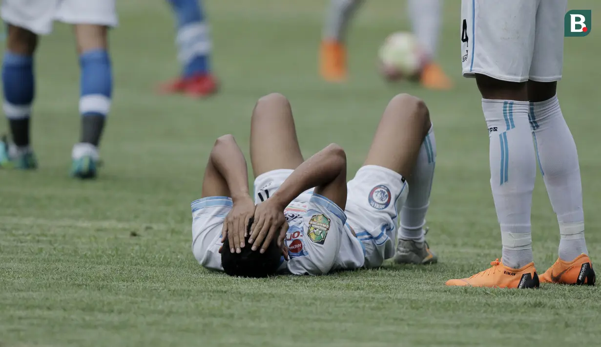 Striker Arema FC, Rivaldi, terbaring di lapangan usai dilanggar pemain Persib Bandung pada laga persahabatan di Stadion GBLA, Bandung, Minggu (18/3/2018). Persib menang 2-1 atas Arema FC. (Bola.com/M Iqbal Ichsan)