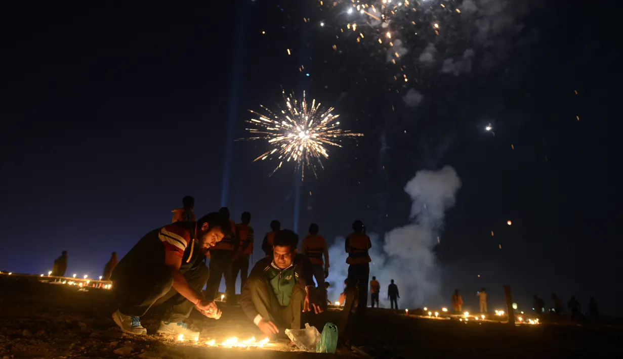 Warga menyalakan lilin dan yang lain melihat kembang api di Sangam saat festival 'Dev Deepawali,' atau festival cahaya, di Allahabad, India, Rabu (25/11).  Festival ini adalah perayaan atas kemenangan kebaikan atas kejahatan. (AFP PHOTO/Sanjay Kanojia) 