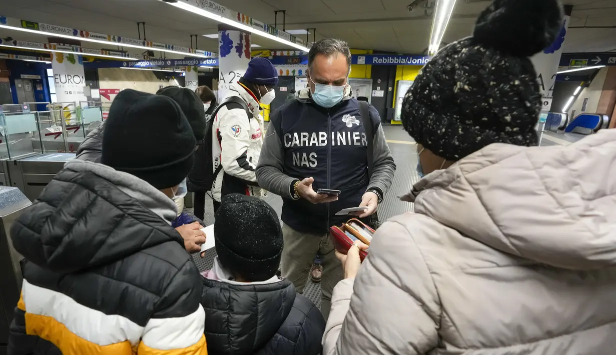Polisi Carabinieri memeriksa kartu kesehatan Covid-19 penumpang pada hari pertama pemberlakuan ‘Super Green Pass’ di Roma, Senin (6/12/2021). Polisi Italia dapat memeriksa apakah pengunjung memiliki Green Pass yang menunjukkan bukti vaksinasi atau kesembuhan dari virus. (AP/Andrew Medichini)