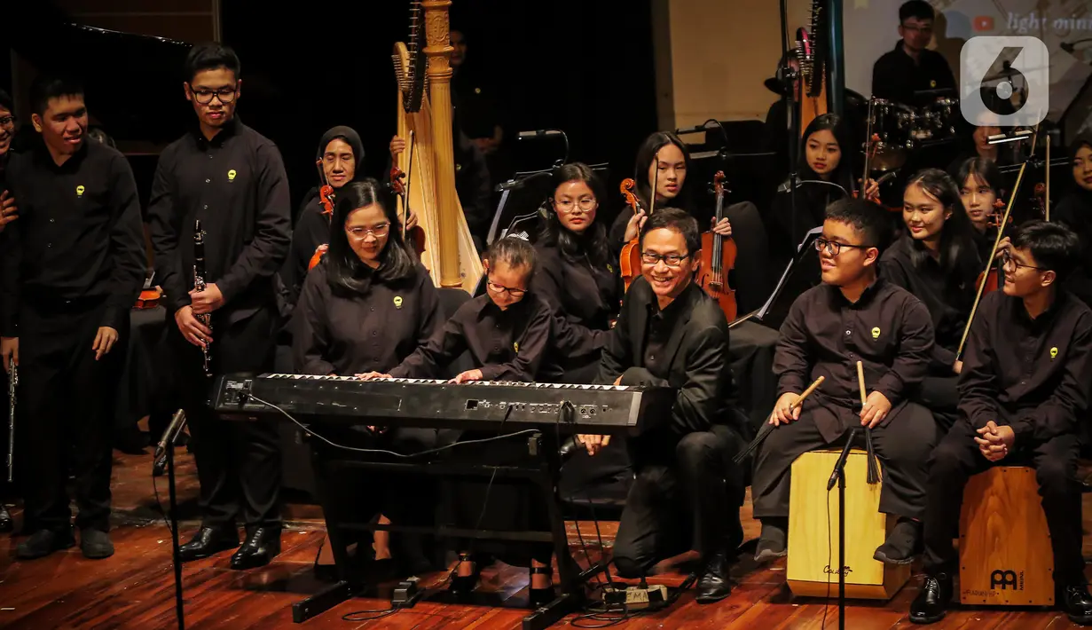 Konduktor Addie MS (tengah kanan) memimpin orkestra grup musik Light Ministry Orchestra (LMO) dan Light Ministry Ensemble (LME), yang mayoritas siswanya berkebutuhan khusus, saat konser A Night of Light di Jakarta, Minggu (19/11/2023). (Liputan6.com/Angga Yuniar)