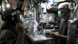 Pedagang alat pelindung wajah atau face shield melayani pembeli di salah satu kios Pasar Pramuka, Jakarta, Rabu (3/6/2020). Face shield di Pasar Pramuka dijual dengan harga mulai Rp 15 ribu hingga Rp 90 ribu per unit. (merdeka.com/Iqbal S. Nugroho)