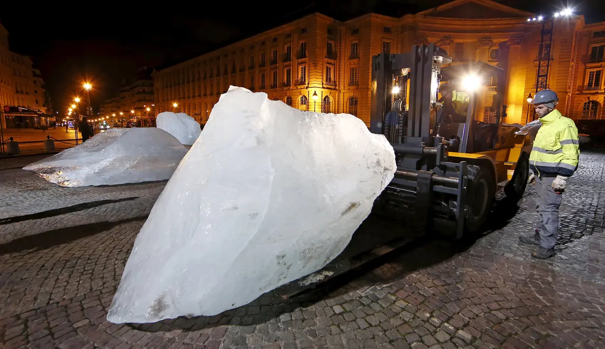 Petugas saat menurunkan balok es untuk ipetunjukkan ke warga Paris yang ada di Place du Pantheon, Perancis, Kamis (3/12). Balok es ini diambil langsung dari daerah Greenland. (REUTERS/Benoit Tessier)