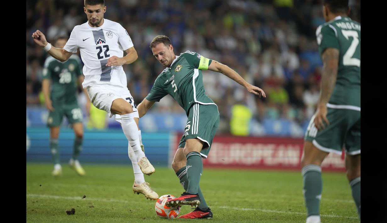 Bek Timnas Irlandia Utara, Jonny Evans (kanan), berhasil mengontrol bola dan menggocek pemain Slovenia, Adam Gnezda Čerin, dalam pertandingan kualifikasi Euro 2024 di Stozice stadium, Ljubljana, Slovenia, Jumat (8/9/2023). Jhonny Evans akhirnya bisa mencetak gol bagi Irlandia Utara dalam pertandingan tersebut. (AP Photo/Darko Bandic)