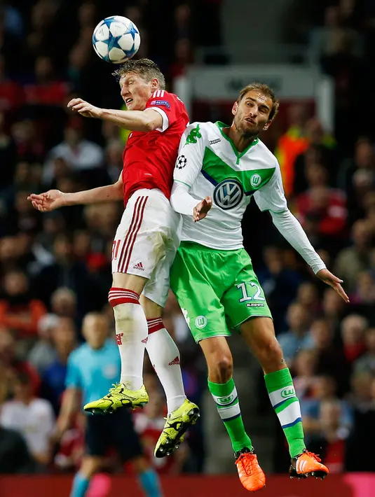 Gelandang MU, Bastian Schweinsteiger berebut bola udara dengan penyerang Wolfsburg, Bas Dost pada laga Liga Champions di Stadion Old Trafford, Inggris, Kamis (1/10/2015). MU menang atas Wolfsburg dengan skor 2-1. (Reuters/Andrew Yates)