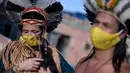 Angoho (kiri) dan suaminya, Hayo mengenakan masker di tengah Pandemi coronavirus novel COVID-19 di Vila Vitoria favela di pinggiran Belo Horizonte, negara bagian Minas Gerais, Brasil (8/7/2020). Angoho dan saudara-saudaranya telah diusir dua kali dari tanah mereka. (AFP/Douglas Magno)