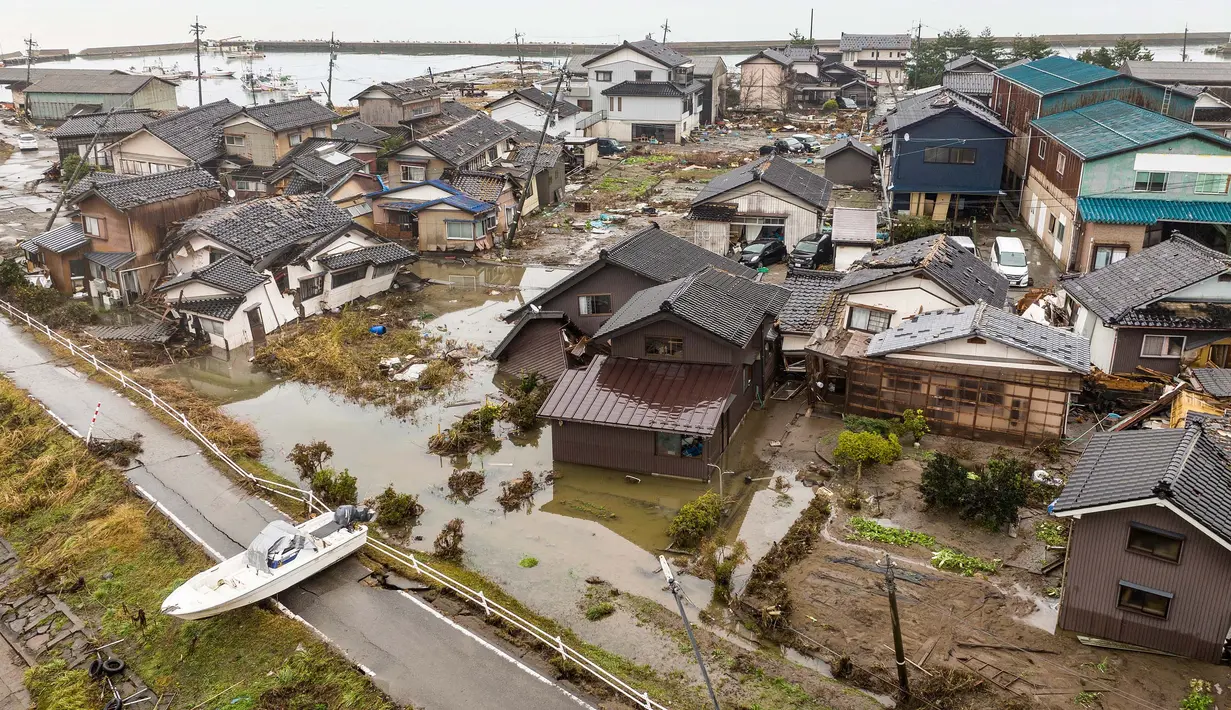 Foto udara ini menunjukkan sebuah kapal terdampar di pantai di sebelah area yang rusak parah di kota Suzu, prefektur Ishikawa pada tanggal 3 Januari 2024. (Fred MERY/AFP)