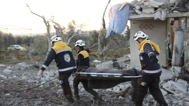 Syrian Civil Defense White Helmets, pekerja pertahanan sipil membawa seorang korban di sebelah rumah yang hancur yang terkena serangan udara Rusia, di desa Maaret Musreen,Idlib, pada Kamis, 5 Maret 2020.