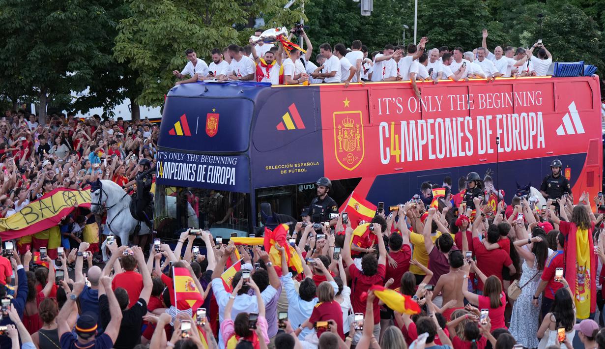 Para pemain timnas Spanyol berparade di dalam bus melintasi pusat kota Madrid saat para penggemar berkumpul untuk merayakan gelar juara Euro 2024, Senin (15/7/2024). (CESAR MANSO / AFP)
