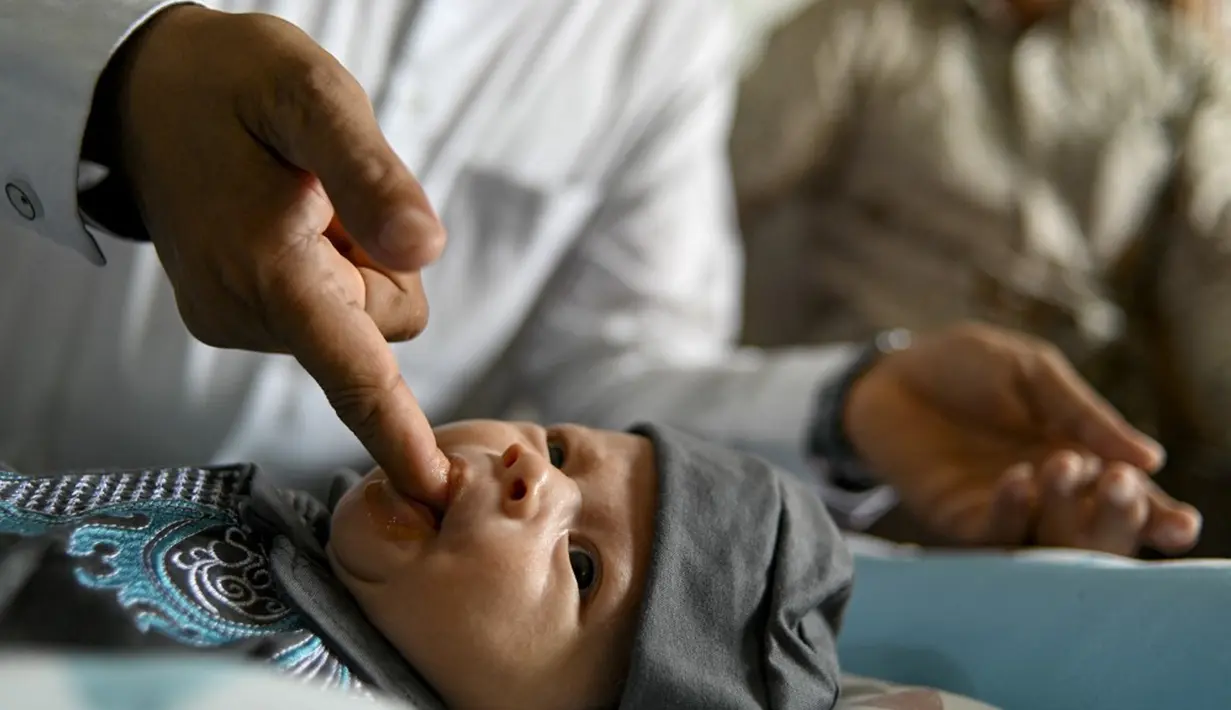 Seorang pria melakukan tahnik dengan memasukkan kurma yang sudah dikunyah ke mulut bayi saat prosesi aqiqah di Banda Aceh, Aceh, 4 November 2021. Aqiqah adalah tradisi menyambut bayi yang baru lahir dalam agama Islam. (CHAIDEER MAHYUDDIN/AFP)