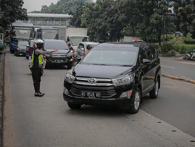 Anggota polisi melakukan penindakan kepada sebuah kendaraan saat ganjil genap di kawasan Jalan D.I Panjaitan, Jakarta, Senin (6/6/2022). Pembatasan mobil dengan sistem pelat nomor ganjil genap di Jakarta diperluas menjadi 25 titik mulai hari ini, Senin, 6 Juni 2022. (Liputan6.com/Faizal Fanani)