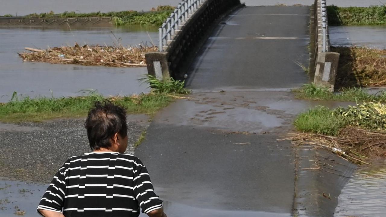 Seorang wanita melihat ke area yang tergenang air akibat luapan sungai di kota Tachiarai, prefektur Fukuoka, Senin (10/7/2023) setelah hujan lebat melanda wilayah Pulau Kyushu.
