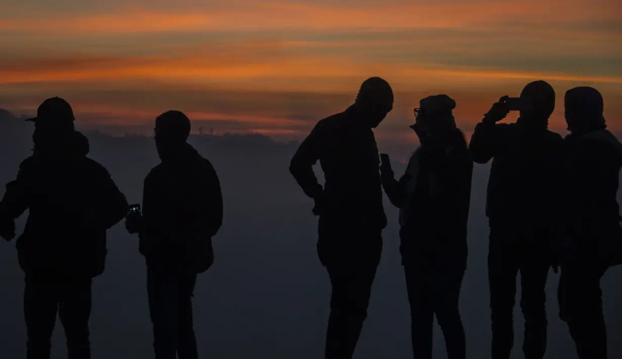 Wisatawan menikmati suasana puncuk Gunung Bromo selama Festival Yadnya Kasada di Probolinggo, Jawa Timur (10/7). Warga Tengger melakukan ritual lempar hasil bumi sebagai wujud syukur pada Sang Hyang Widi. (AFP Photo/Juni Kriswanto)