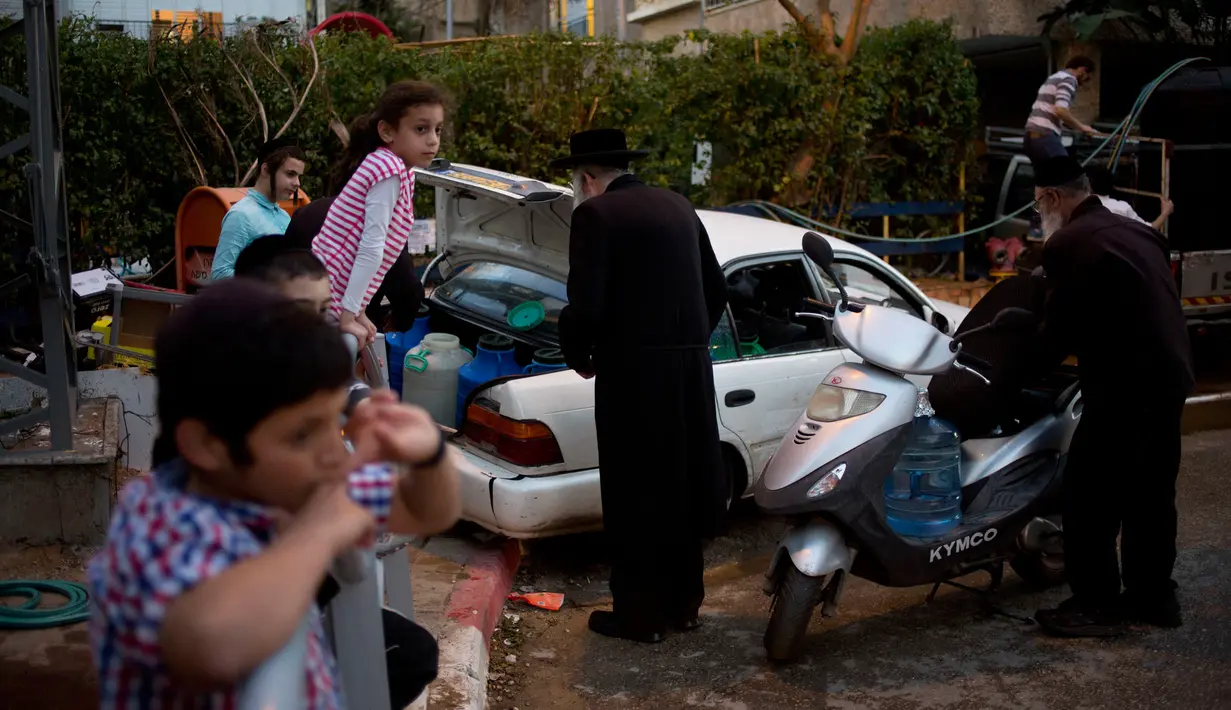Penganut Yahudi ultra-Ortodoks bersiap membawa air dengan kendaraan mereka untuk membuat matza di dekat Tel Aviv, Yerusalem (4/4). Dalam perayaan Paskah Yahudi mereka dilarang memakan makananan yang berbahan beragi. (AP Photo/Sebastian Scheiner)