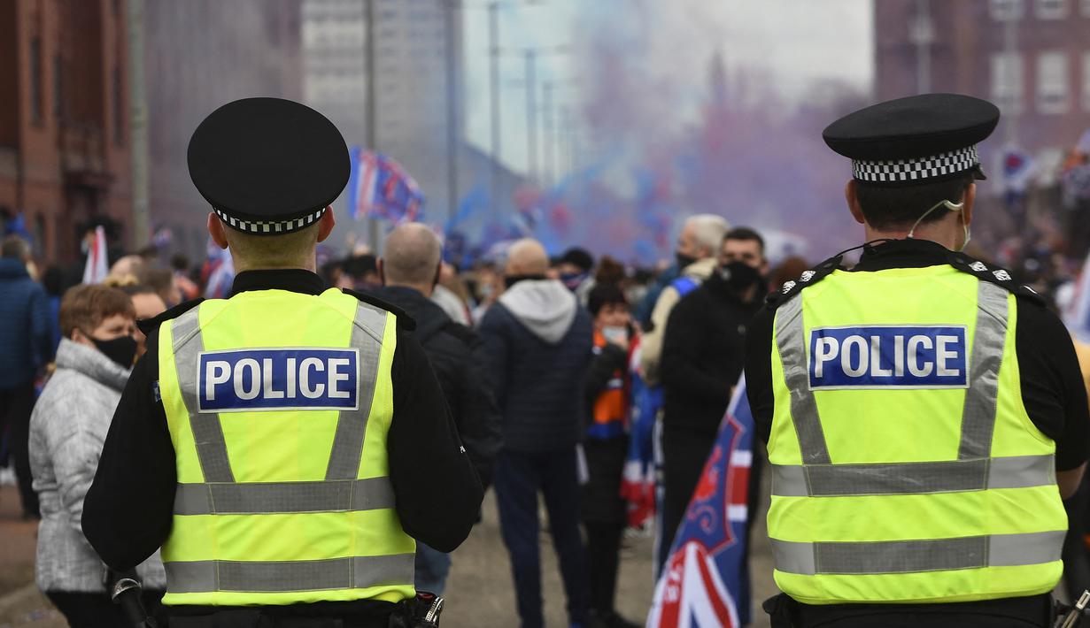 Petugas kepolisian melakukan patroli terhadap para fans Glasgow Rangers di luar Ibrox Stadium (7/3/2021) dalam perayaan keberhasilan tim kesayangan mereka merebut gelar Liga Utama Skotlandia setelah memimpin 20 poin dari saingan terdekat, Glasgow Celtic. (AFP/Andy Buchanan)