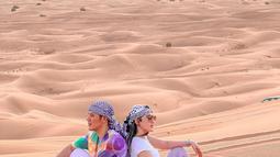 Via Vallen dan Chevra Yolandi berpose saling membelakangi punggung, Via dan Chevra terlihat candid dengan memandang padang gurun pasir. (Instagram/viavallen)