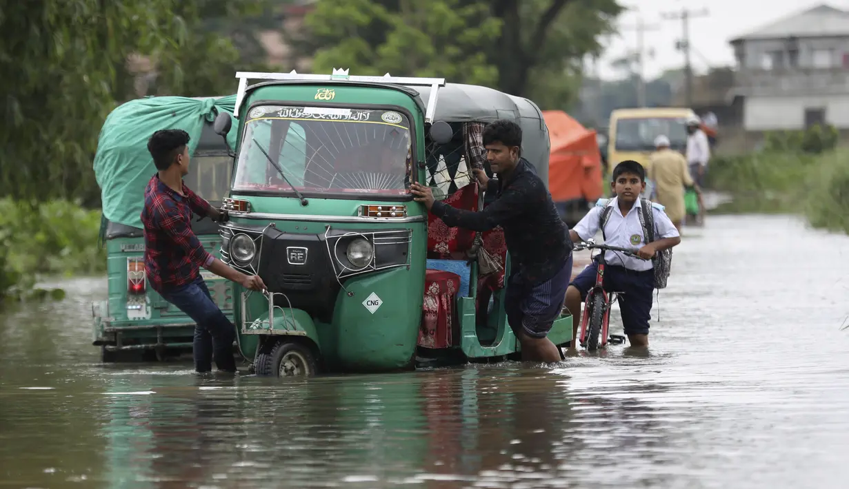 Orang-orang mendorong becak mobil melalui jalan yang banjir di daerah Bagha di Sylhet, Bangladesh (23/5/2022). Banjir bandang pra-musim telah membanjiri bagian dari India dan Bangladesh, menewaskan sedikitnya 24 orang dalam beberapa pekan terakhir dan mengirim 90.000 orang ke tempat penampungan. (AP Photo)