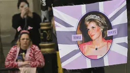 Para simpatisan, salah satunya memegang spanduk bergambar mendiang Diana, Princess of Wales, berbaris di rute Prosesi penobatan Raja Charles III  di London, Sabtu (6/5/2023).  (Sebastien Bozon/Pool Photo via AP)