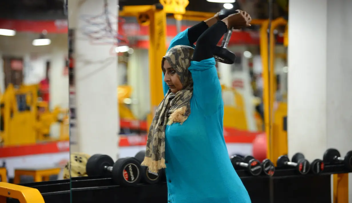Seorang wanita Muslim India mengangkat beban saat berlatih di gym Ahmedabad Fitness Academy (AFA) di Ahmedabad (10/5/2019). Selama bulan suci Ramadhan, tempat gym ini tetap buka hingga larut malam untuk membiarkan anggota Muslim berolahraga setelah salat. (AFP Photo/Sam Panthaky)