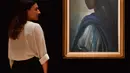 Karyawan rumah lelang Bonhams berdiri dekat lukisan seorang putri Nigeria bernama Tutu di London pada 7 Februari 2018. Mona Lisa dari Afrika itu sempat hilang bertahun-tahun sebelum ditemukan di apartemen London belum lama ini. (BEN STANSALL/AFP)