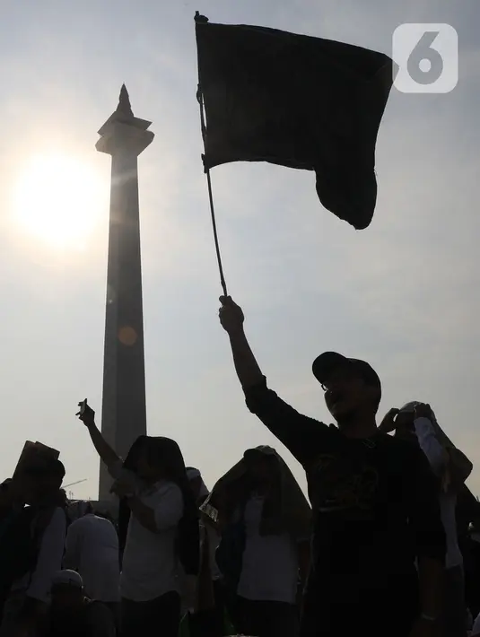 Massa mengibarkan bendera saat mengikuti acara Munajat dan Maulid Akbar 2019 #ReuniMujahid212 di kawasan Monas, Jakarta, Senin (2/12/2019). Aksi dimulai dengan salat tahajud bersama pada pukul 03.00 WIB dan ditutup dengan doa yang berakhir pada pukul 08.00 WIB. (Liputan6.com/Herman Zakharia)